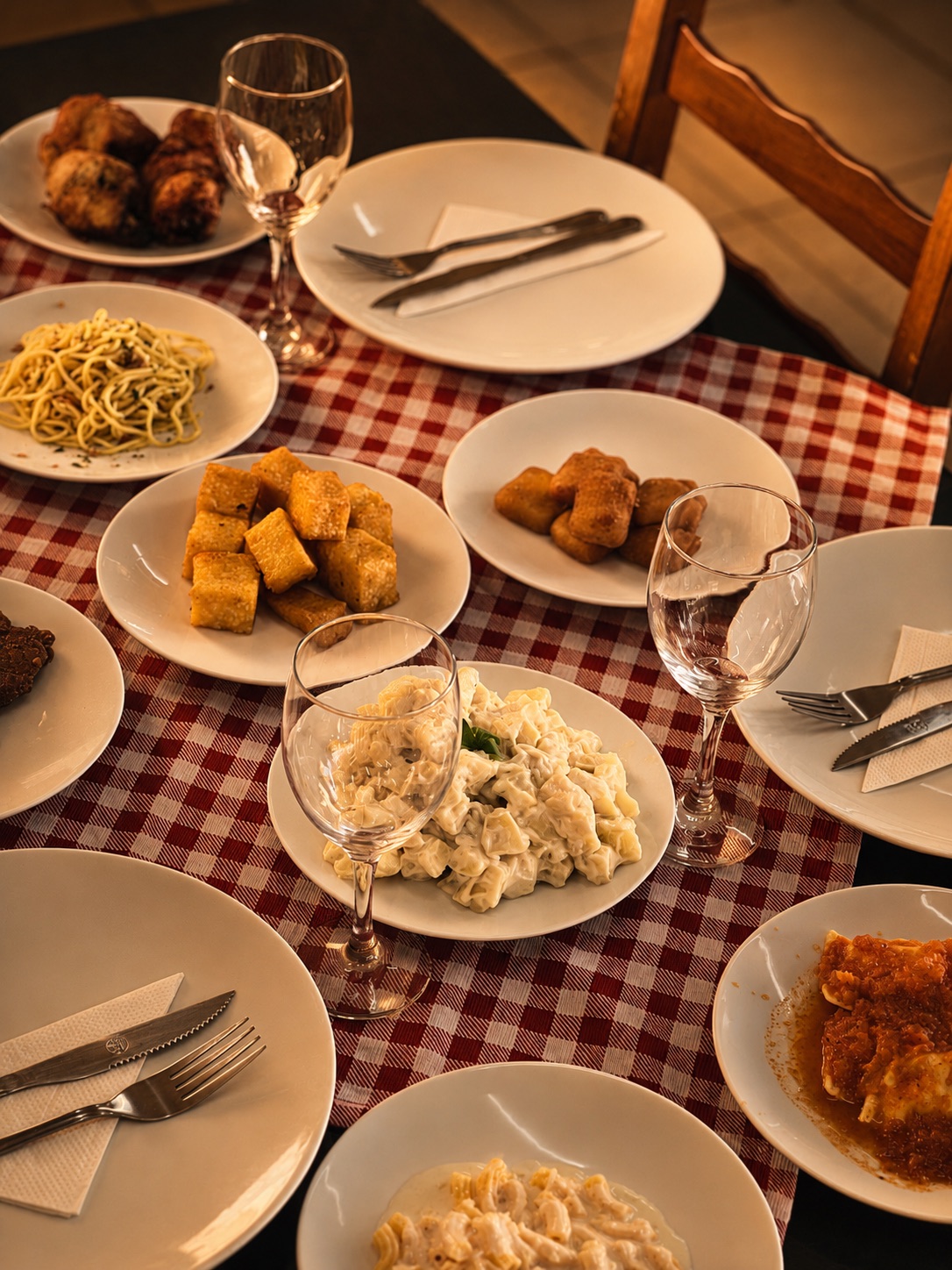 Mesa de domingo do La Casa com massas, acompanhamentos e taças de vinho.